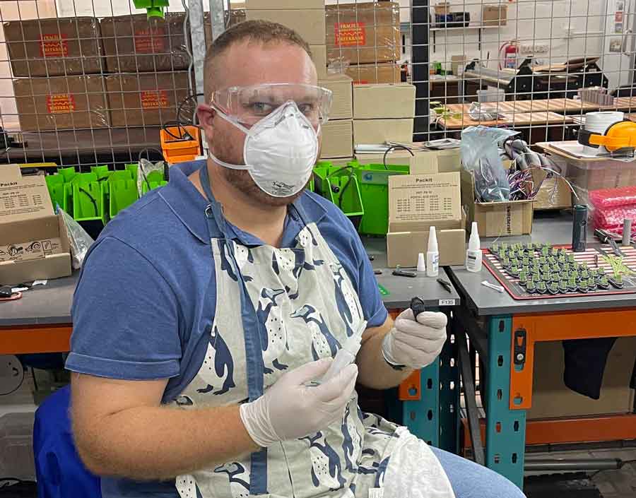 Andrew at his workspace, surrounded by electronics and tools.